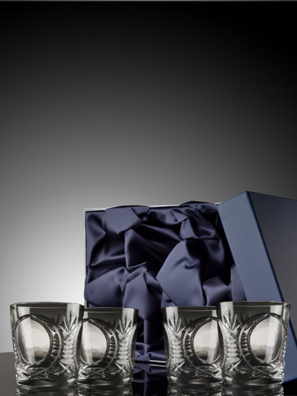 Set of four Bothwell crystal glasses with a blue satin bow in an open box on a dark background