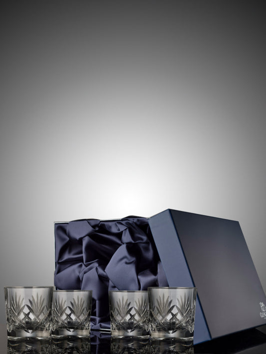 Set of Edinburgh crystal glasses with a dark blue satin ribbon and box on a grey background